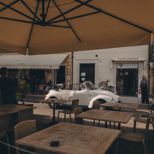 Die Braut fährt mit weißem Oldtimer zur Hochzeit