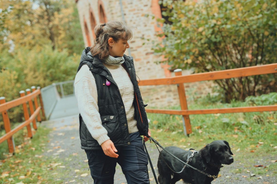 Hundetrainerin läuft mit ihrem Hund durch den Park