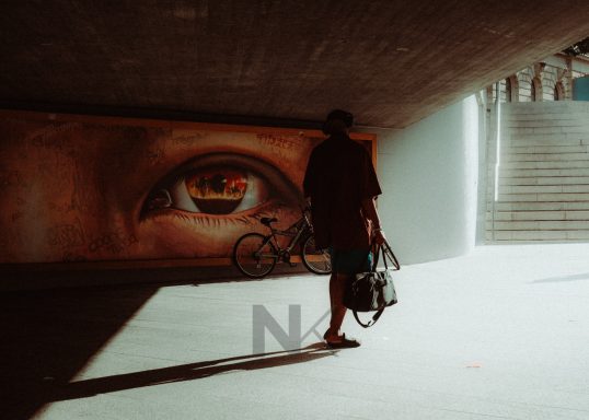 Person läuft vor Kunstwerk mit Auge