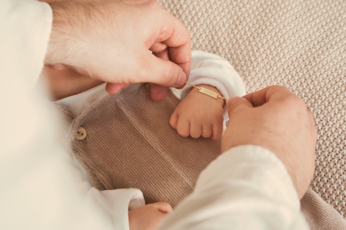 Vater macht dem Neugeborenem ein Armband um