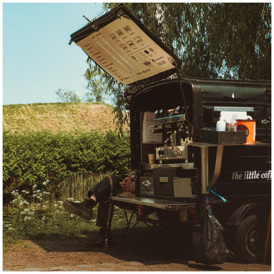 Beine eines Mannes schauen hinter dem Kaffeewagen hervor